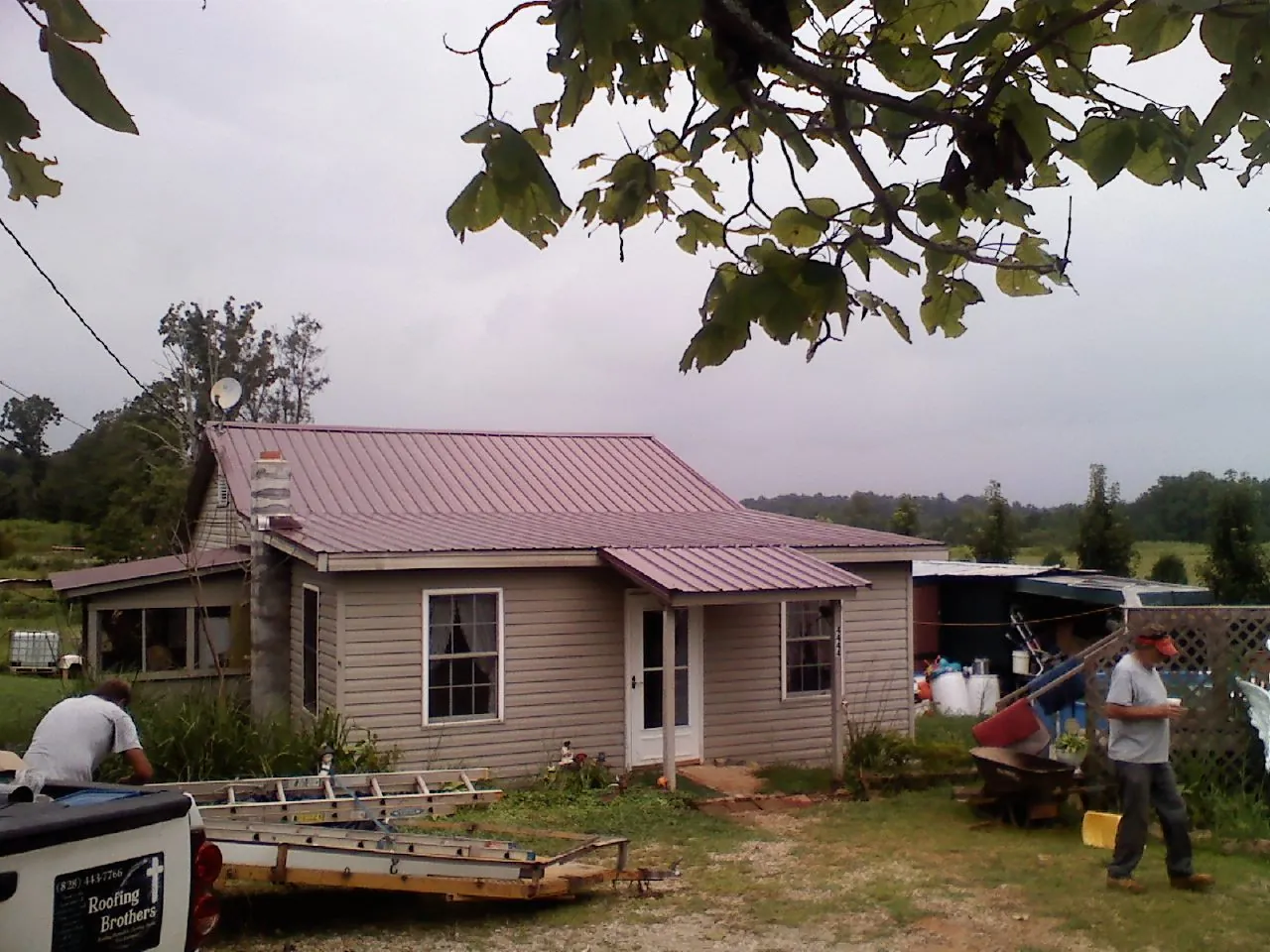 Crew finishing a mauve metal roof on a small farmhouse in Blackstock