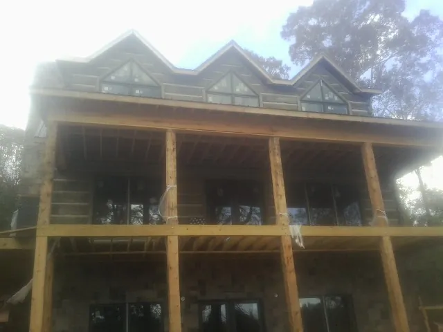 Dormers and porch framing on a large log home under construction — Roof Coating work by our crew in Blackstock