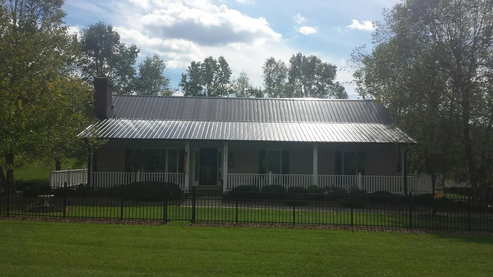 Gray metal roof on a brick ranch with a full width front porch — Gutter Guard Installation work by our crew in Blackstock
