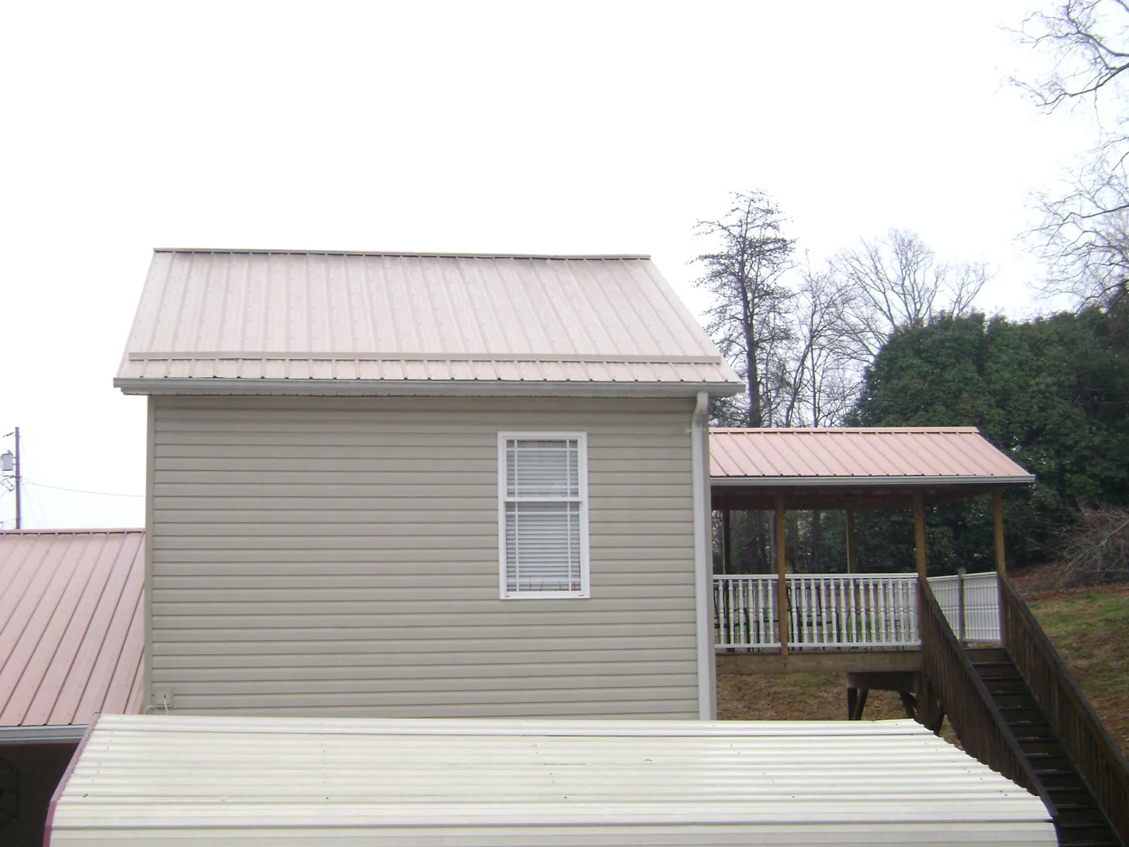 Tan metal roofs on a two story addition and attached porch, from a Roof Replacement job in Blackstock