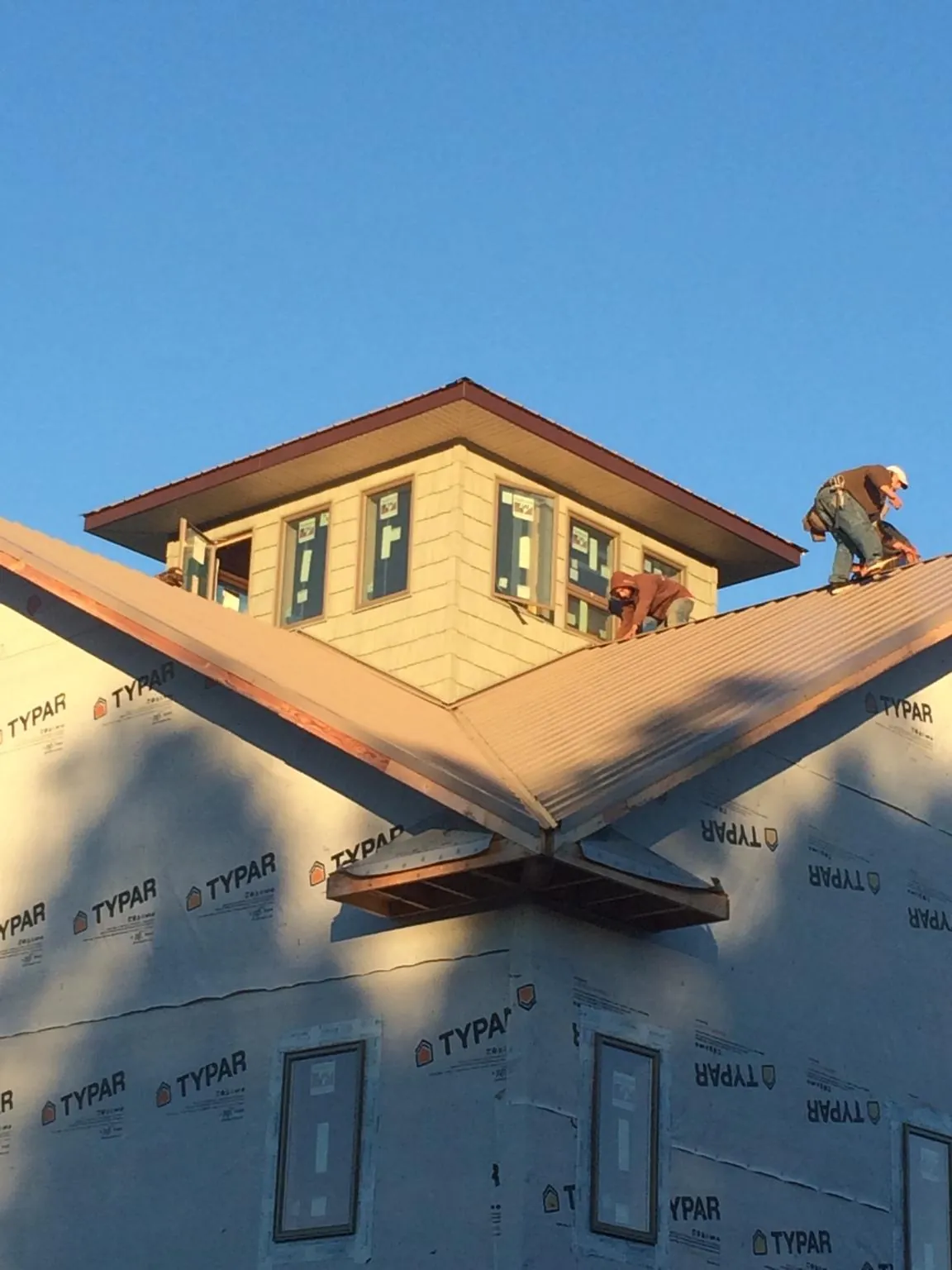 Roofers working around a rooftop cupola on a new metal roof at sunset — Roof Waterproofing in Blackstock by Roofing Brothers